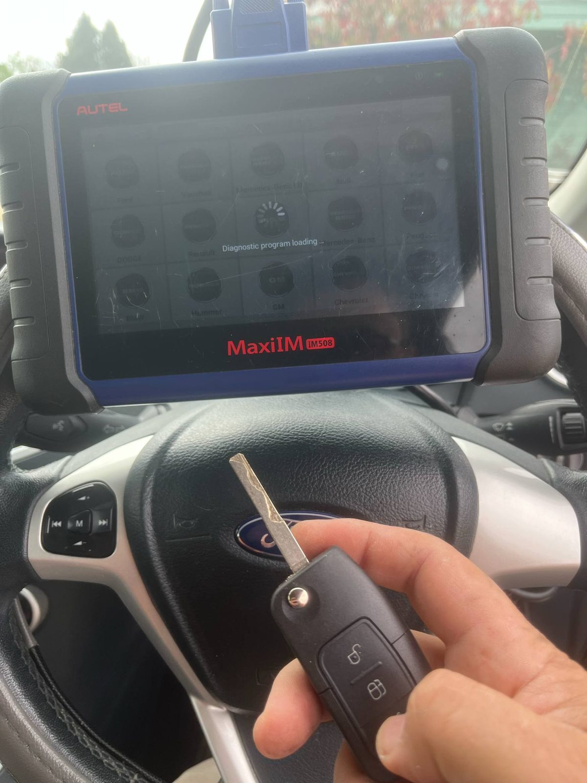 Newly cut and programmed Ford Fiesta flip key held next to the diagnostic tablet used to program it