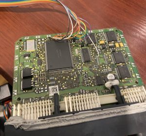 ECU circuit board connected with coloured jumper wires for bench programming and repair