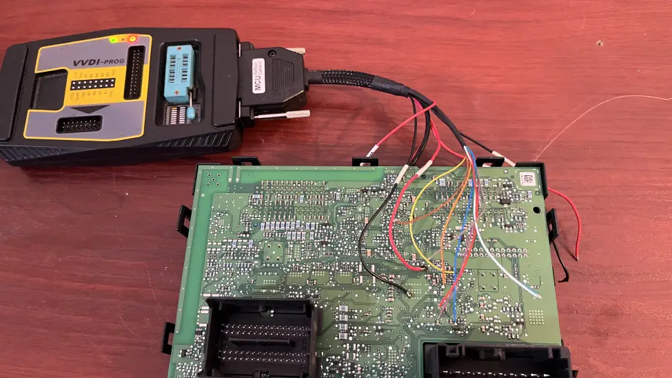 Automotive BCM module wired to VVDI-Prog for EEPROM read and repair on workbench in Evesham