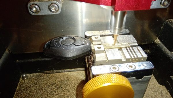 Key cutting machine carving a car key blade for automotive locksmith service