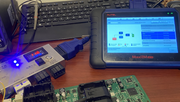 Automotive ECU module connected to diagnostic and programming tools on workbench